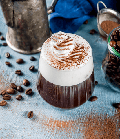 a coffee cocktail in a glass cup with a creamy, foamy head sprinkled with chocolate.