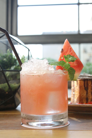 The watermelon mint mojito, a cocktail with a pleasing pink color and a watermelon wedge as garnish. 