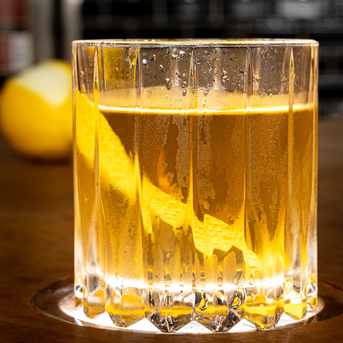 Old Fashioned Cocktail with an orange peel. On a wooden table.