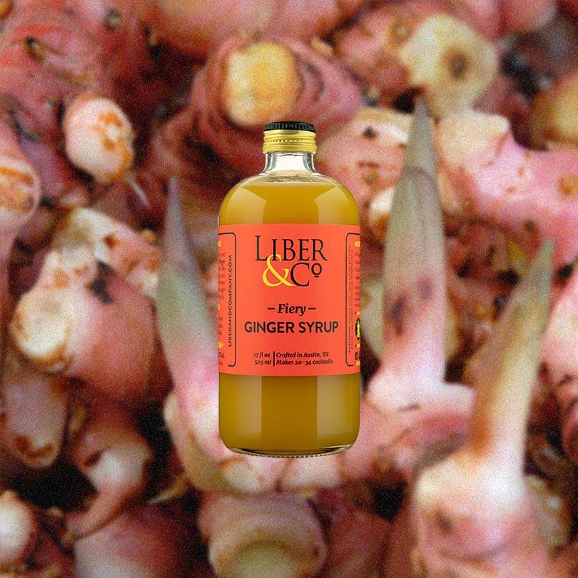 Bottle of Liber & Co. Fiery Ginger Syrup over backdrop of ginger root.