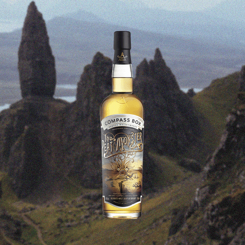 Bottle of Compass Box Peat Monster over backdrop of mountains and valleys.