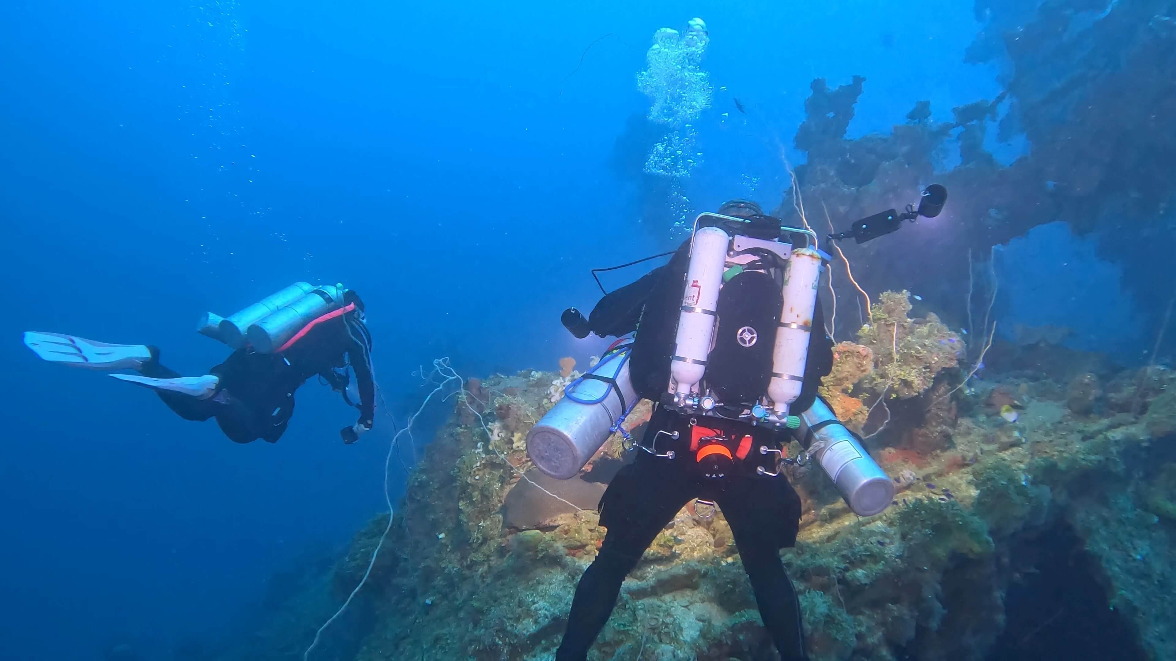 2 Divers Swimming Around A Wreck