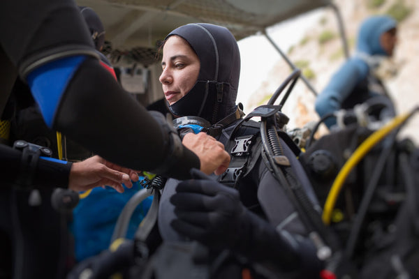 woman preparing to dive off a boat getting her equipment checked