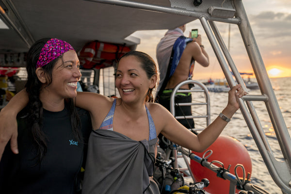 two women smiling with arms around each other on a dive boat