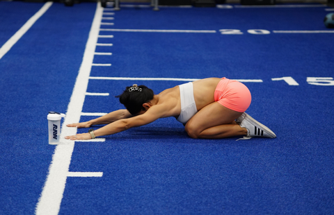 Stephanie Ayala McHugh doing stretching on the floor in the gym