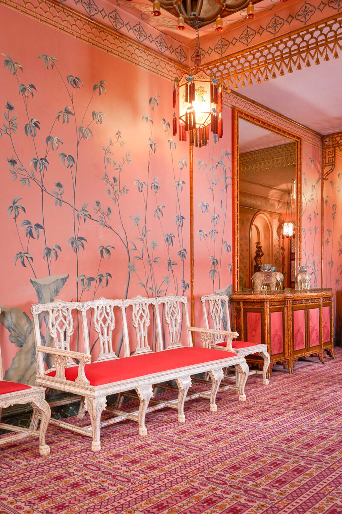 Maximalist interiors of Brighton Pavilion featuring pink and blue chinoiserie wallpaper and pint antique furniture