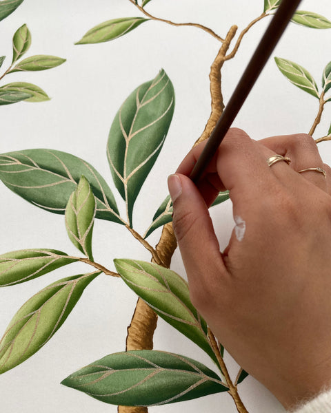 Diane Hill hand-painting green Chinoiserie leaves on silk wallpaper for her Harlequin wallpaper mural 'Florence'