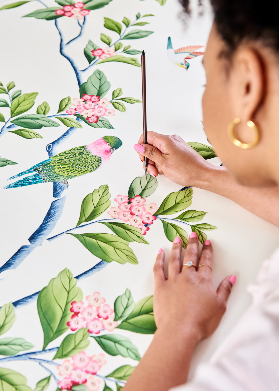 Diane Hill painting colourful chinoiserie birds and leaves onto silk paper