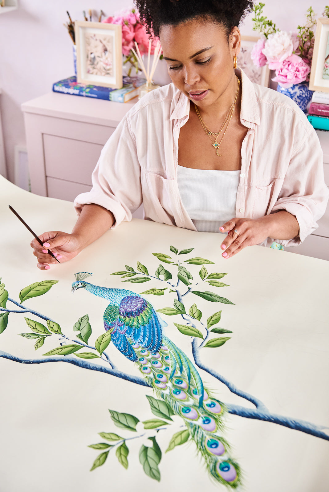 Diane Hill painting a chinoiserie peacock motif onto silk wallpaper