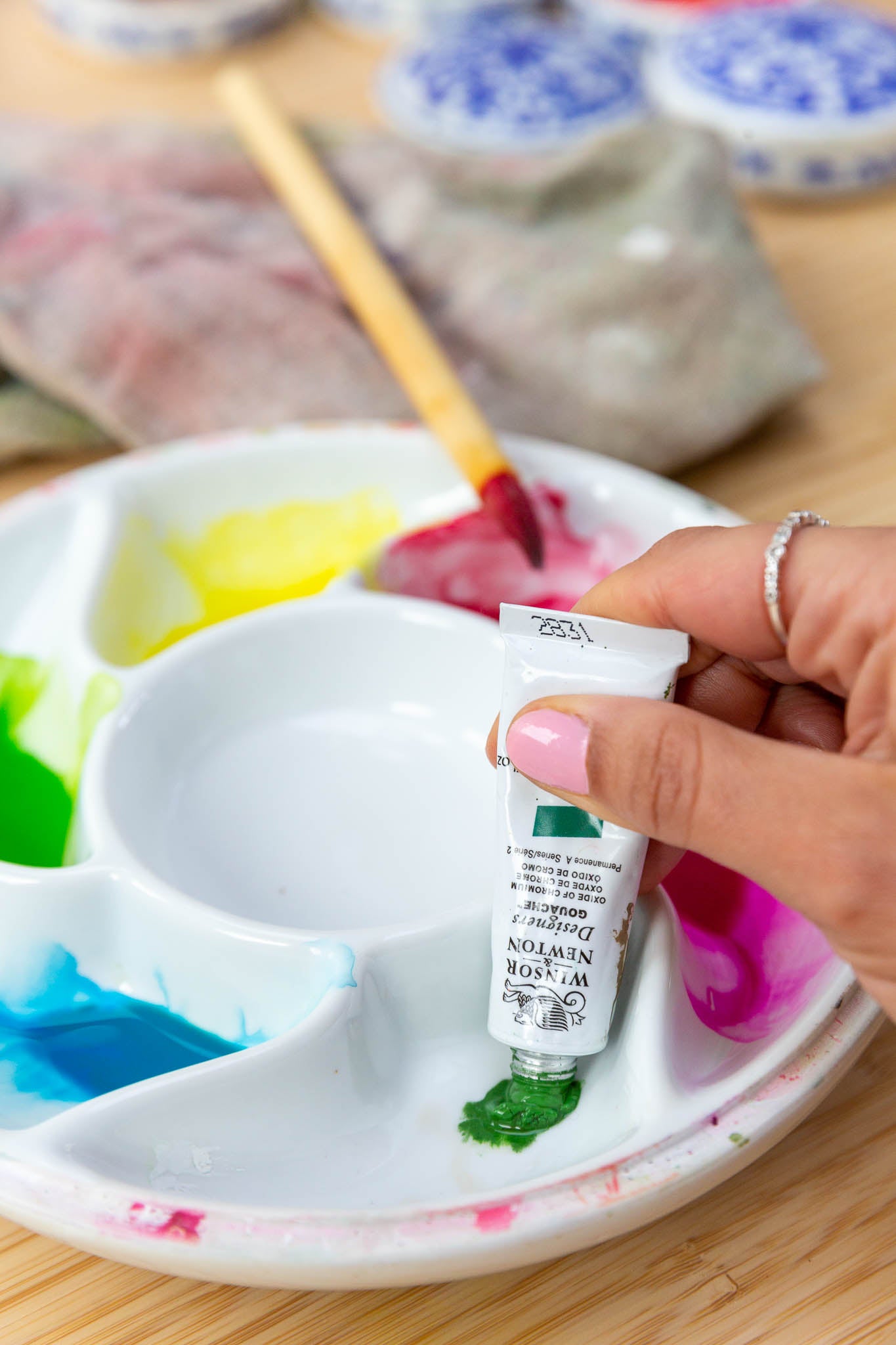 hand squeezing gouache watercolor paint into paint palette