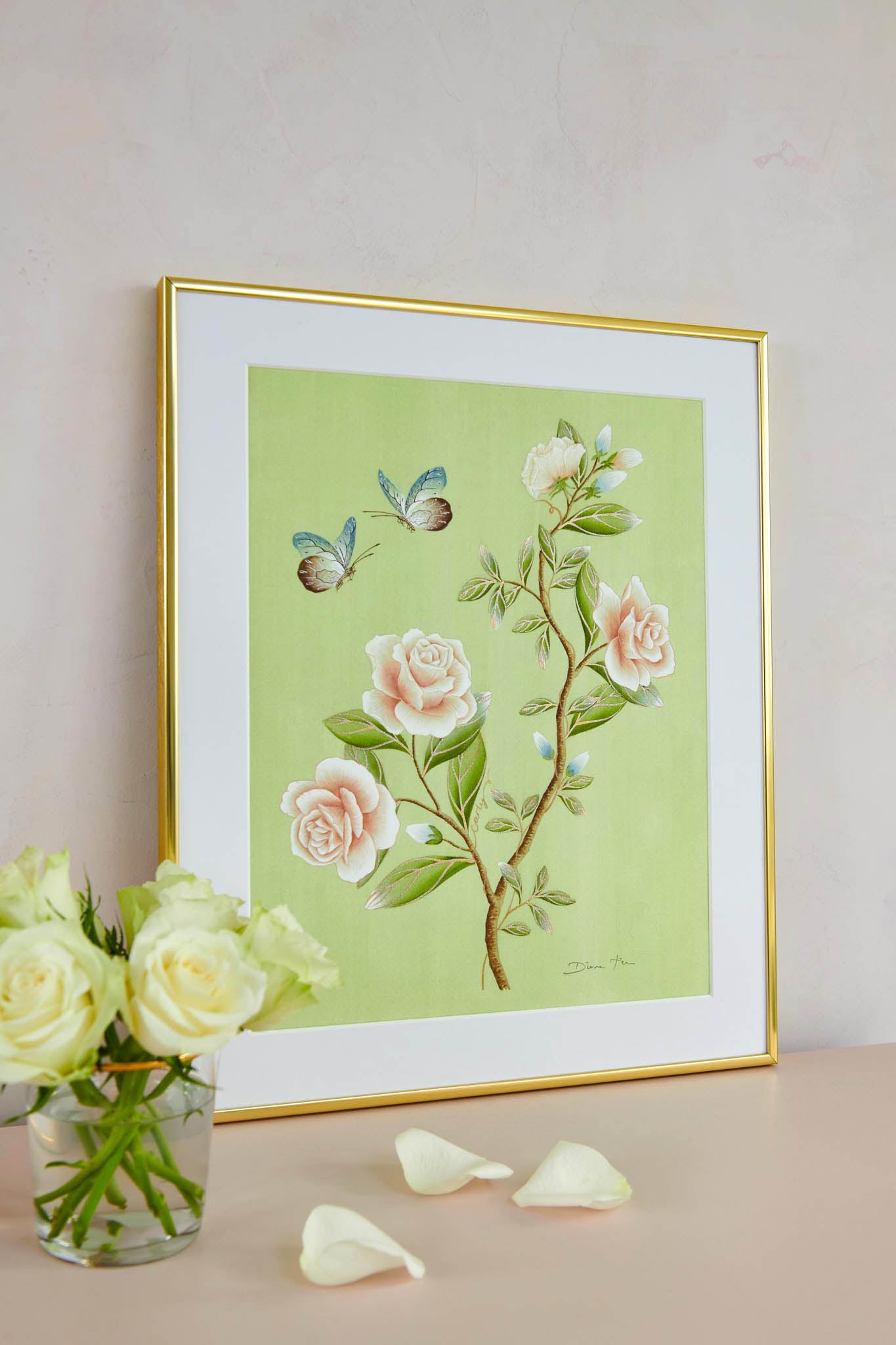 Diane Hill's 'Carly' embellished chinoiserie art print in gold frame on a table with a vase of white roses