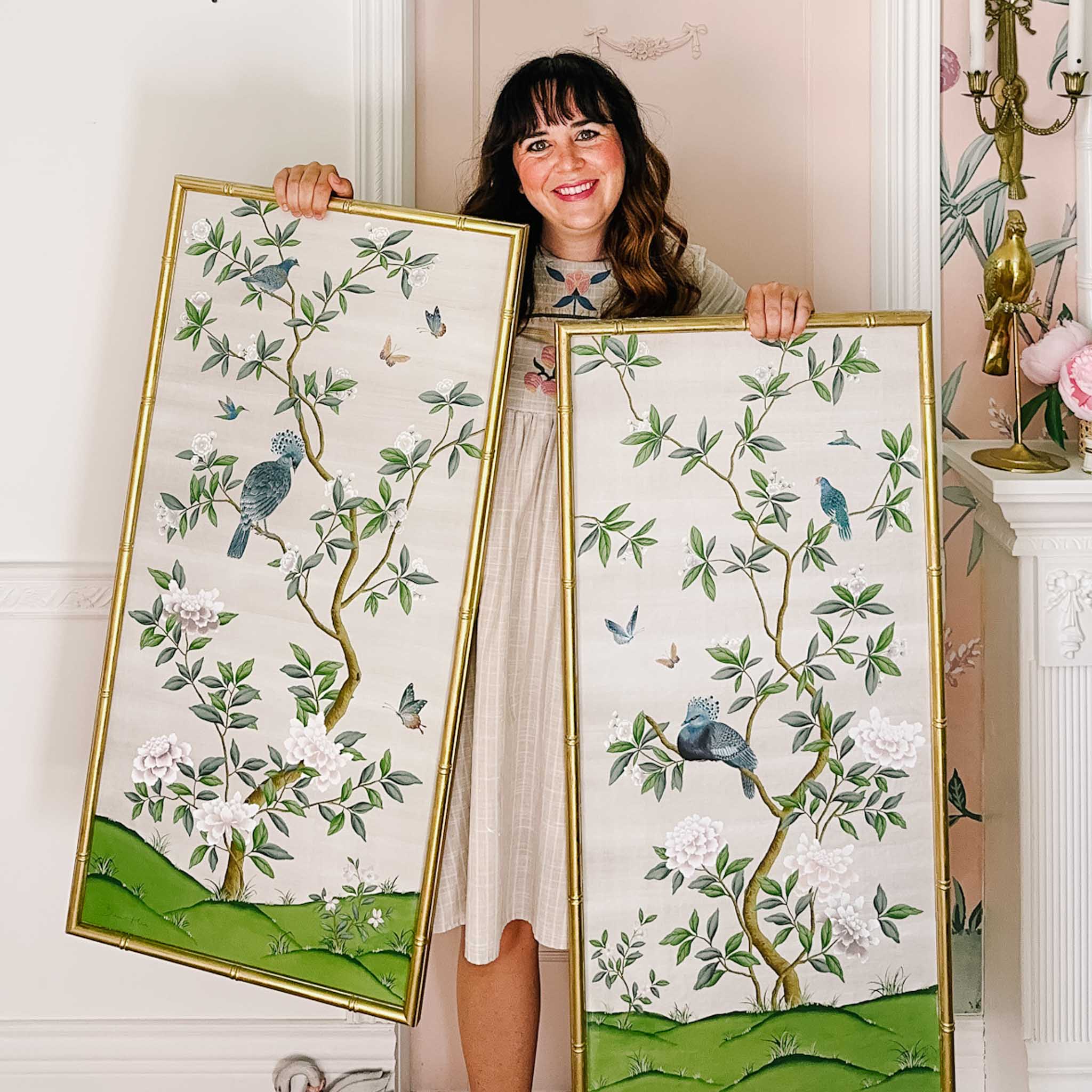 Blogger 'At Home With Ashley' holding up her two DIY framed chinoiserie panels