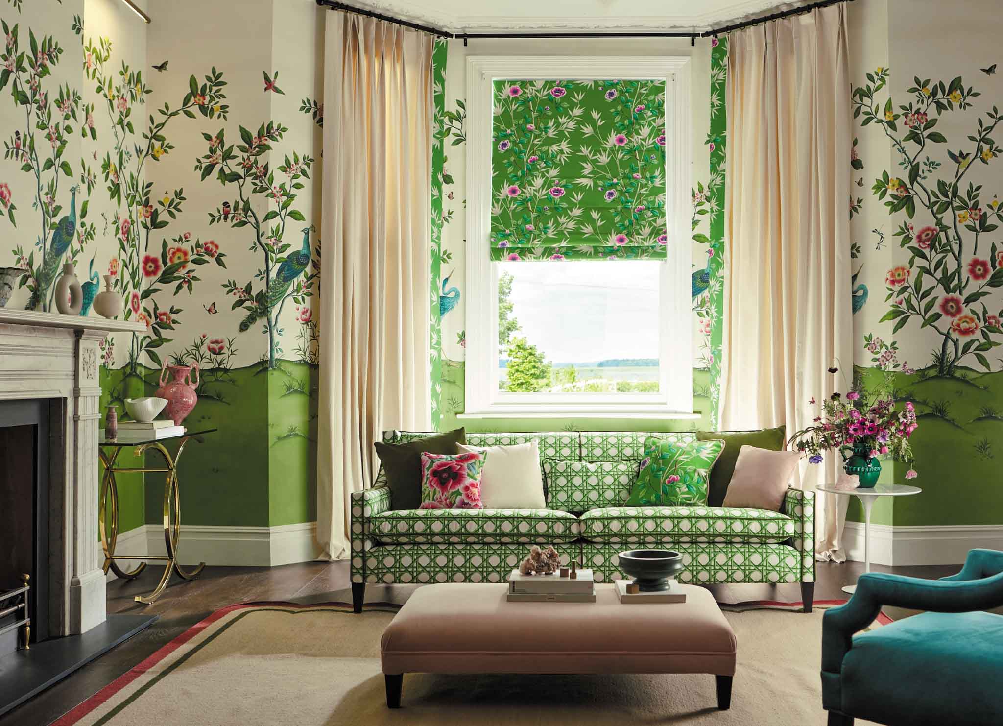 Chinoiserie wallpaper 'Florence' on all four walls of a living room, decorated in green and pink tones and featuring Chinoiserie trees, birds and flowers. Part of the Harlequin X Diane Hill range of wallpaper and fabric.