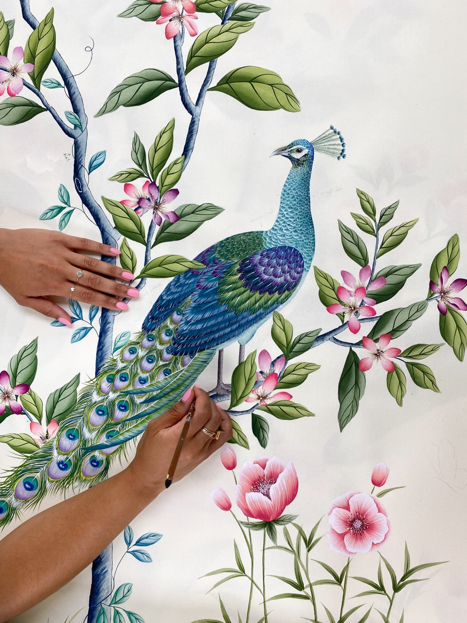 Diane Hill hand painting a chinoiserie peacock and floral design onto silk paper