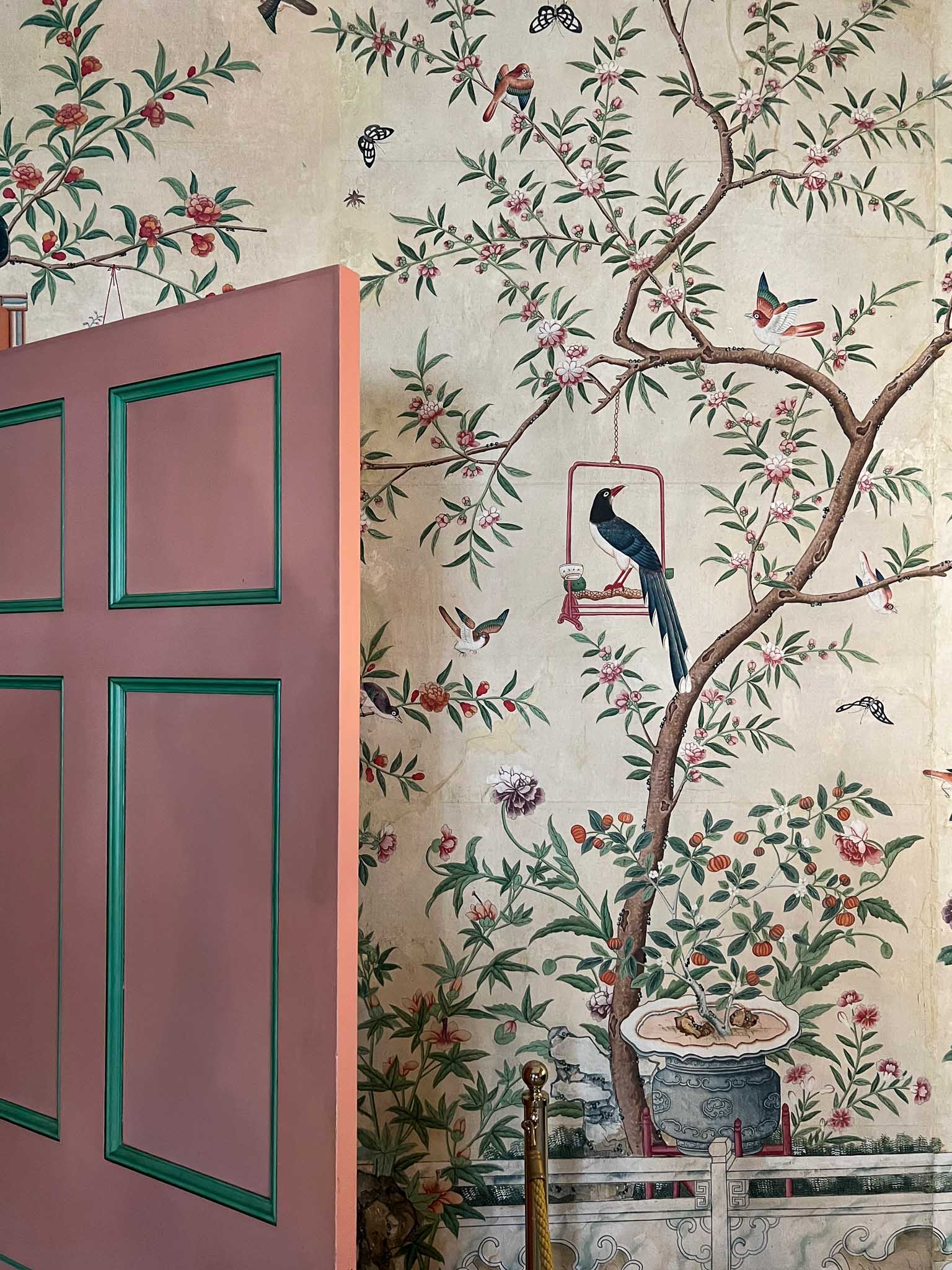 Colourful chinoiserie wallpaper inside Queen Victoria's bedroom at Brighton Pavilion with a pink door