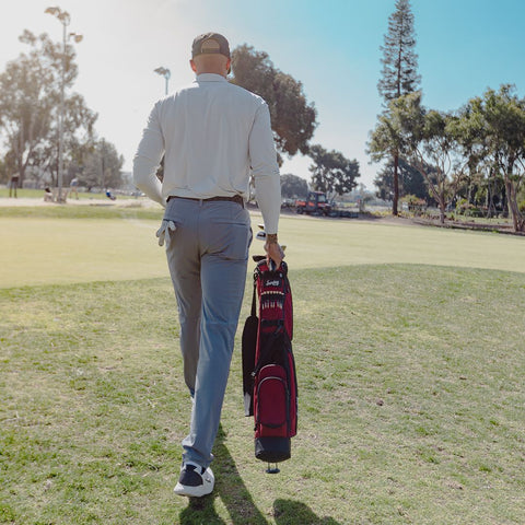 man walking and carrying a lightweight golf bag