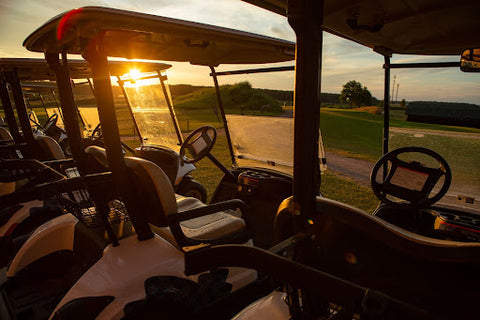 golf carts lined up by a golf course