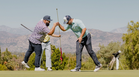 2 guys celebrating on the course while playing golf with a hand fist