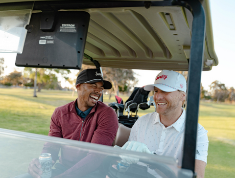 two guys laughing and sitting in their golf cart