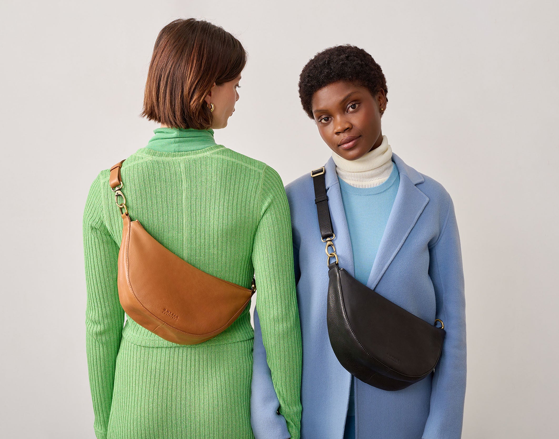 Two models wearing Leo bags, soft grain slouchy leather bag