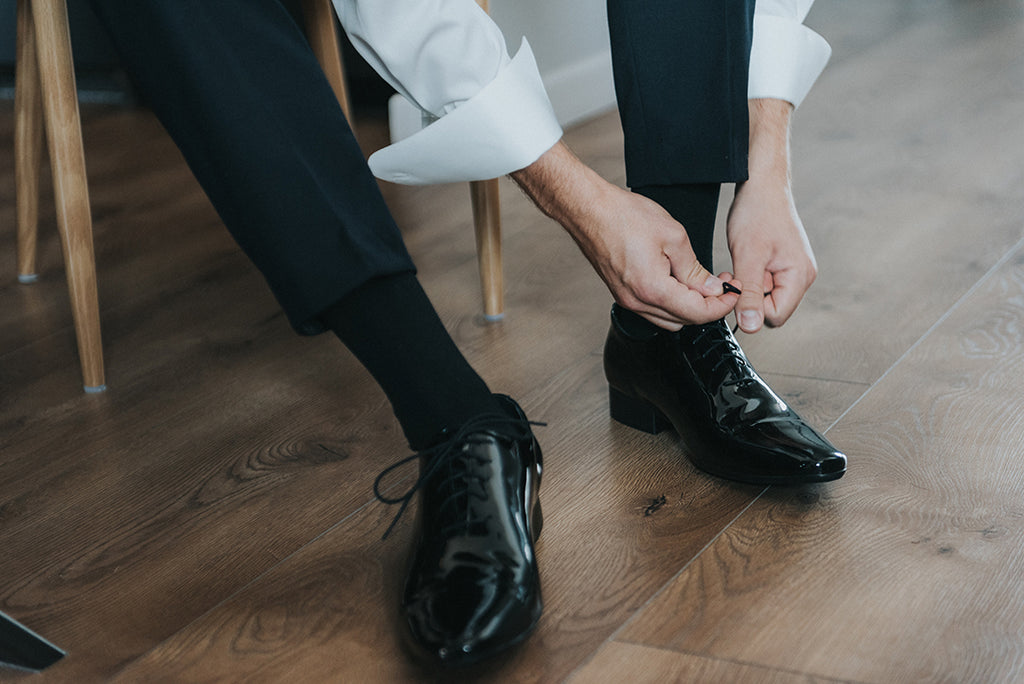 Man tying black Oxford shoe