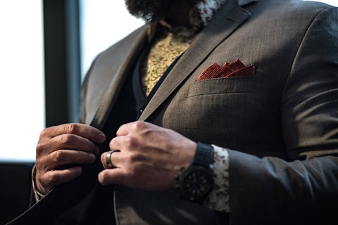 man in suit with pocket square buttoning up