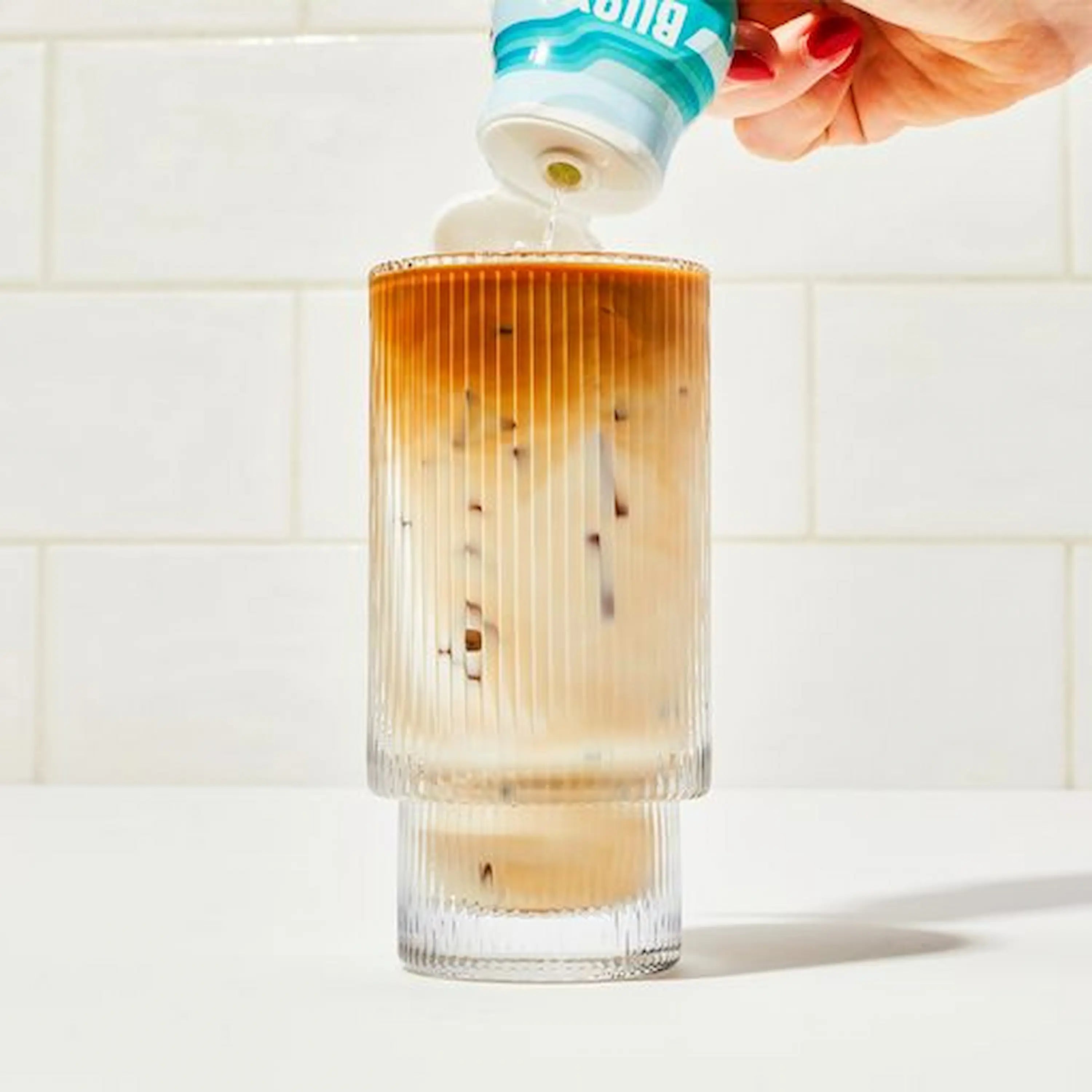 Squeezing Buoy hydration drops into iced coffee.