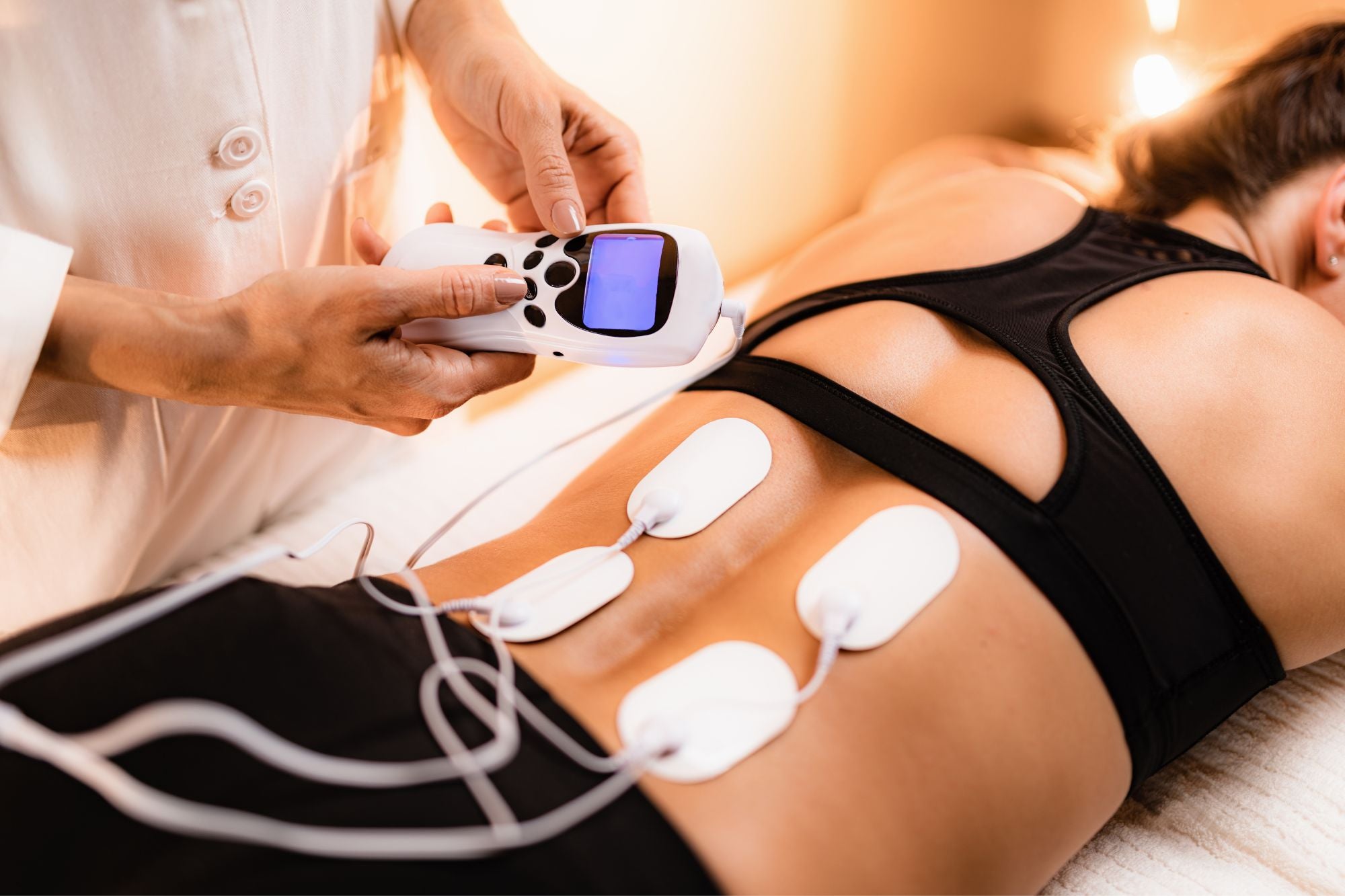 A patient undergoing physical therapy with electrical stimulation therapy pads on their back.