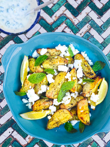 Plate of potato wedges with feta cheese and mint leaves