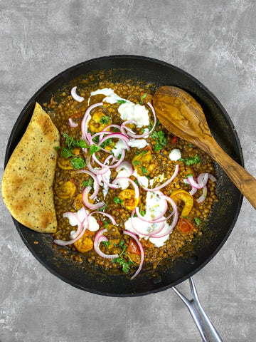 Sartén de lentejas al curry con pan naan y cebolla