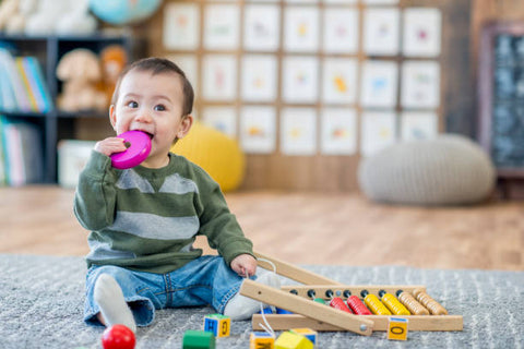 Young asian boy with a baby toy in his mouth