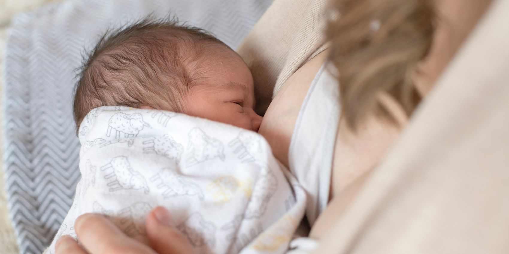 Closeup of woman breastfeeding a newborn baby in a hospital bed