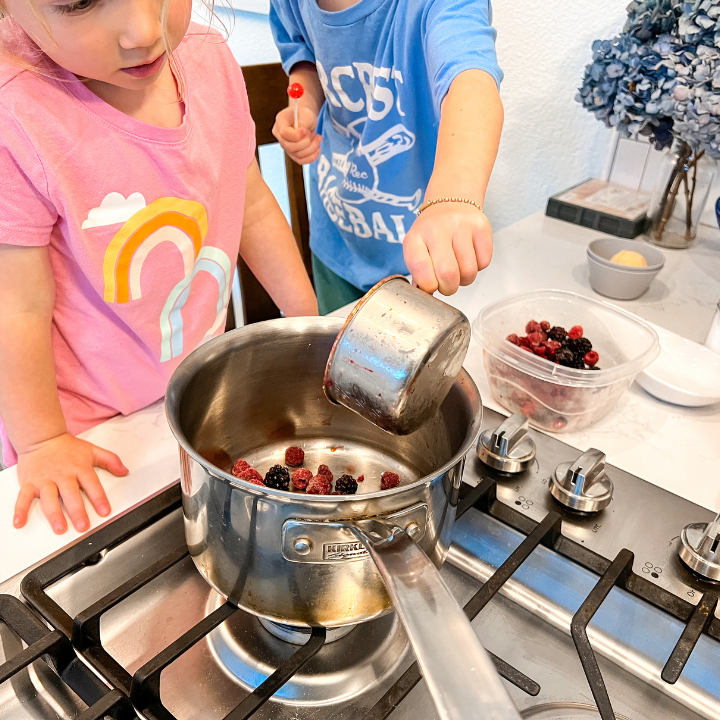 Two kids adding ingredients into a bowl to make a pie