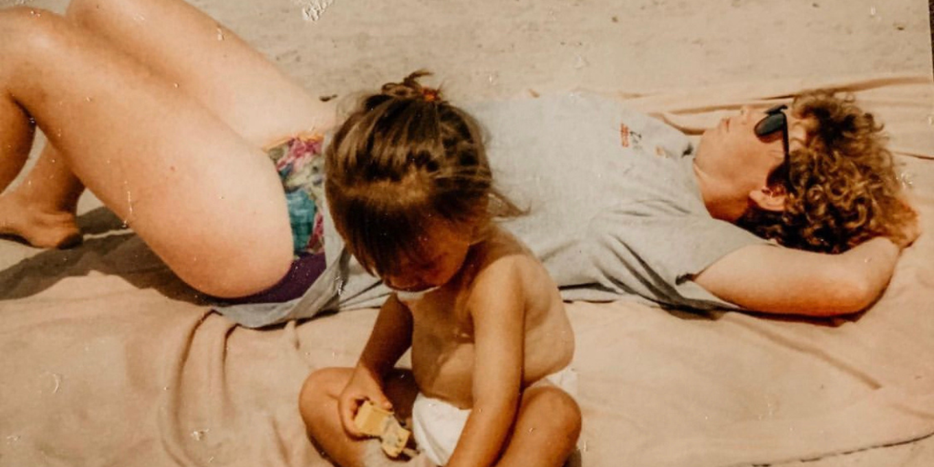 Lo Rivas as a toddler laying on the beach with her mother