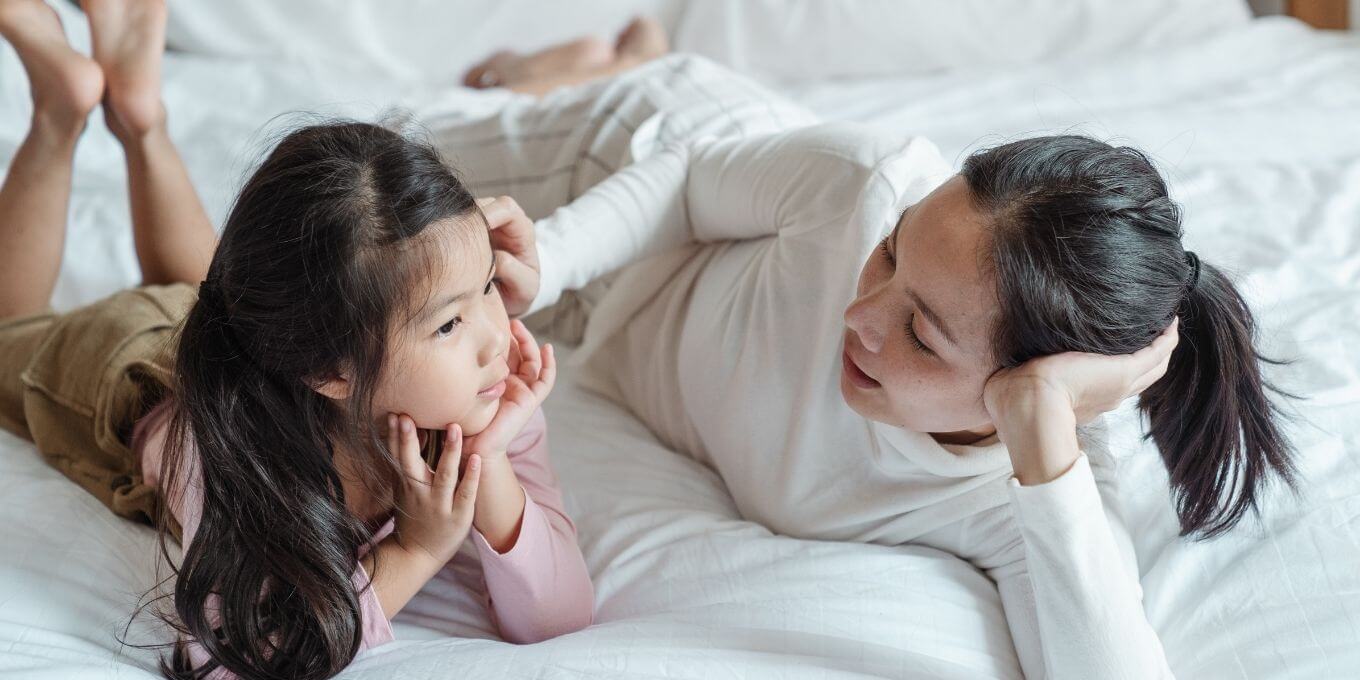 Mother and daughter sitting on a bed talking