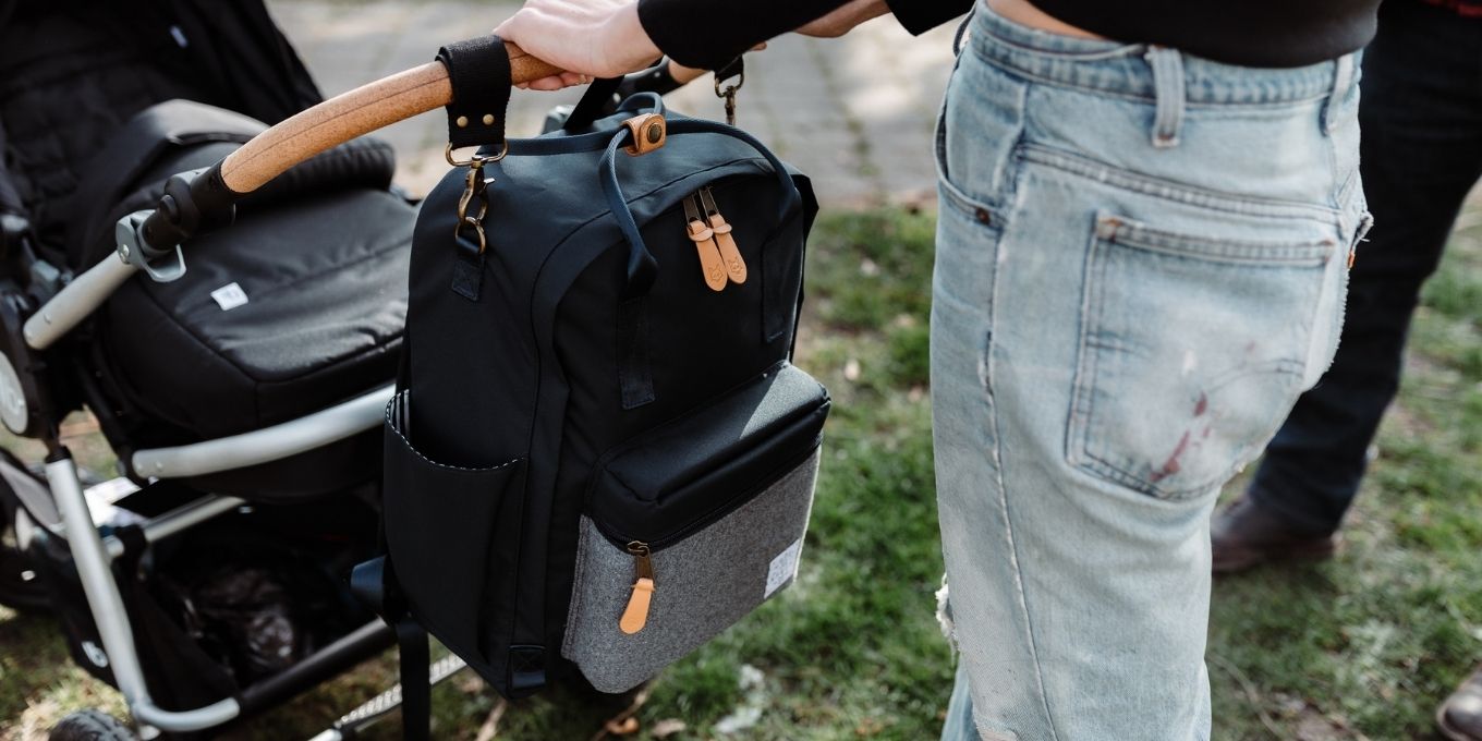 Navy Elkin Diaper Bag strapped to a stroller that young woman is pushing