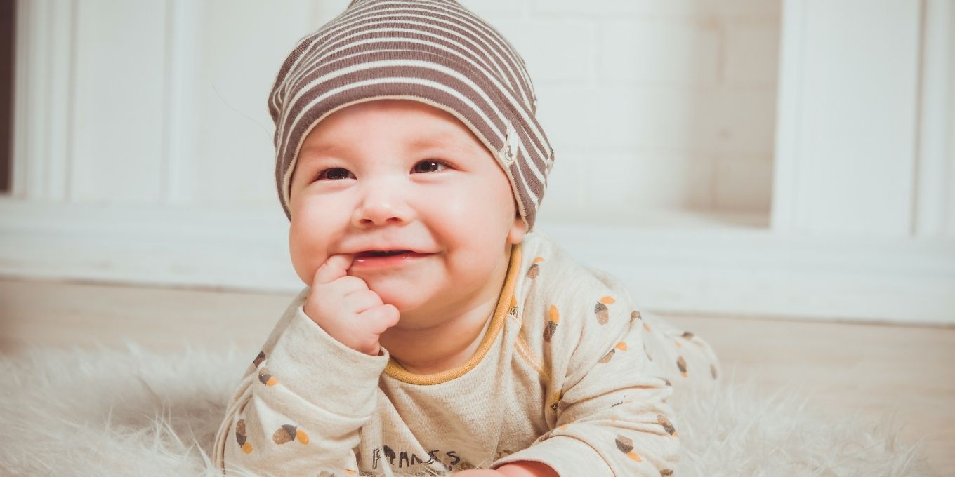 Image of baby boy laying on rug smiling