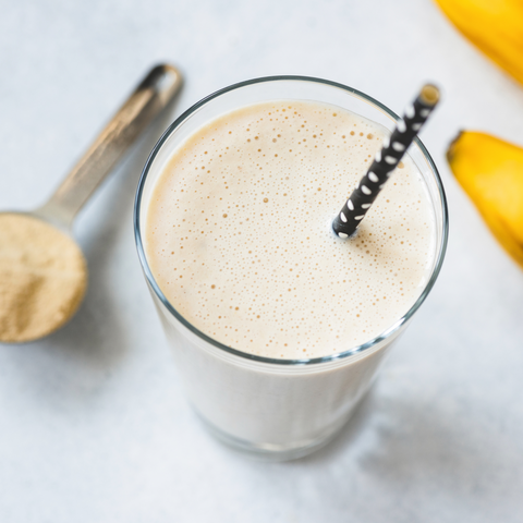 Protein shake with bananas and protein powder scoop.