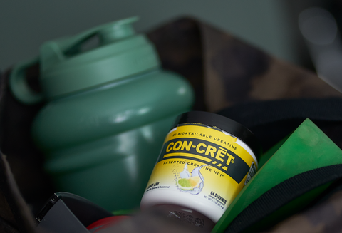 CON-CRET Creatine bottle in a gym bag with a water jug.