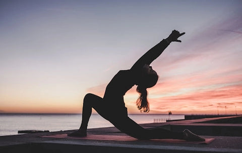 Silhouette of a woman doing yoga during sunset on the beach.