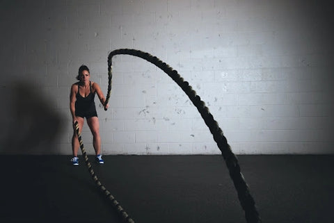 A photo of a woman exercising with ropes.
