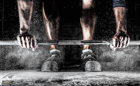 Chalk powder surrounding a weightlifter gripping a bar.
