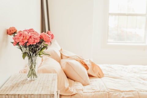 Bouquet of pink roses next to a bed to symbolize how to elevate your home decor with fragrances.