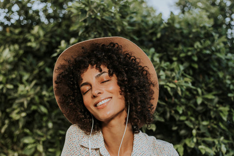 Photo of a woman outdoors with sun on her face and tree in background