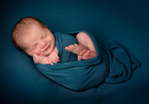 a baby wrapped in blue blanket on a blue background