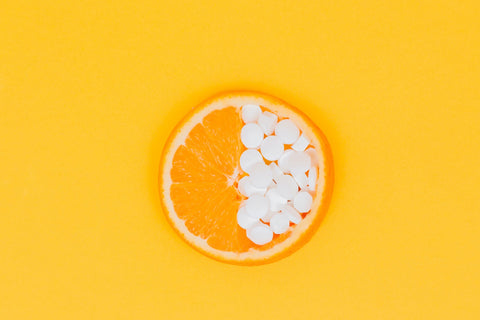 vitamin c pills on a slice of an orange with orange background