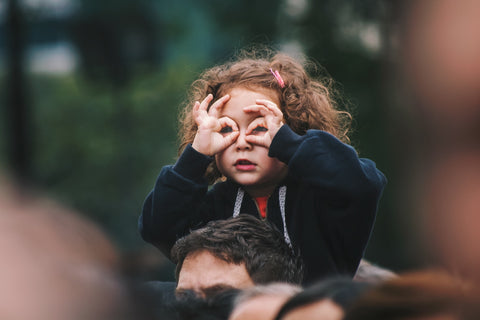 A kid making glasses with her hands.