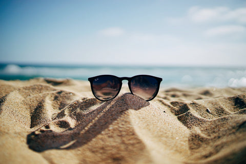 sunglasses lying on sandy sea shore