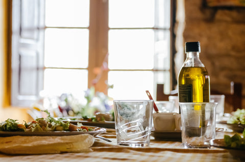 a bottle of olive oil on a table next to a salad