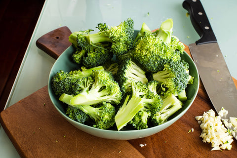 Broccoli in a bowl with a knife.